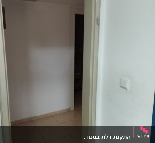 דלת פתוחה עם משקוף בהיר וקיר לבן